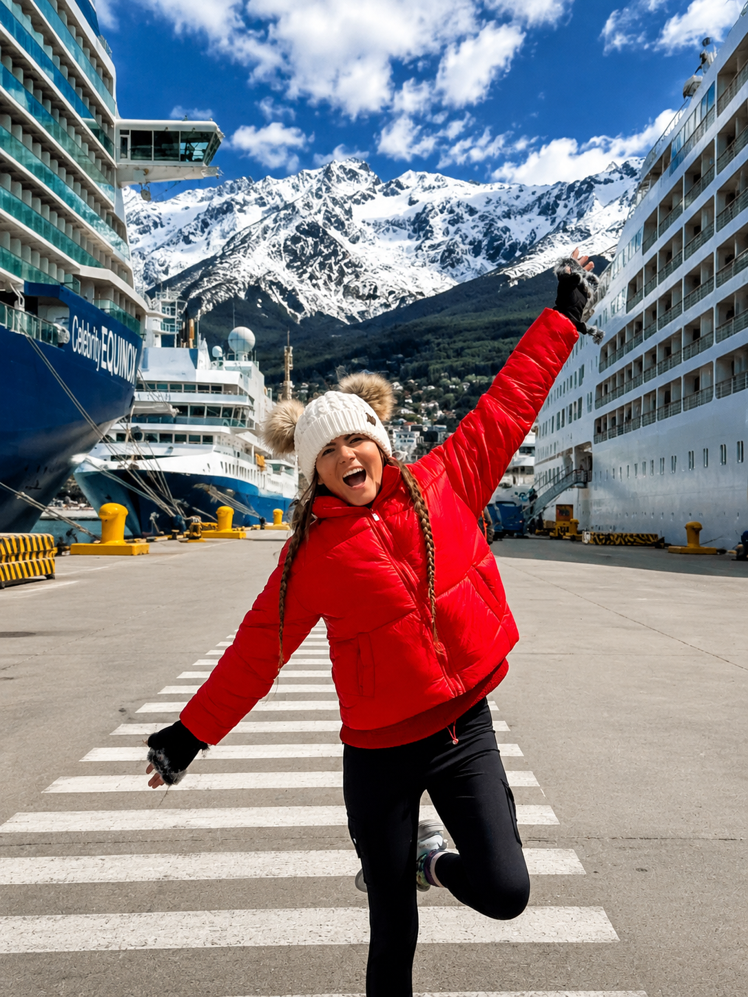 Cassie in a red jacket in front of cruise ships and snowy mountains in Ushuaia